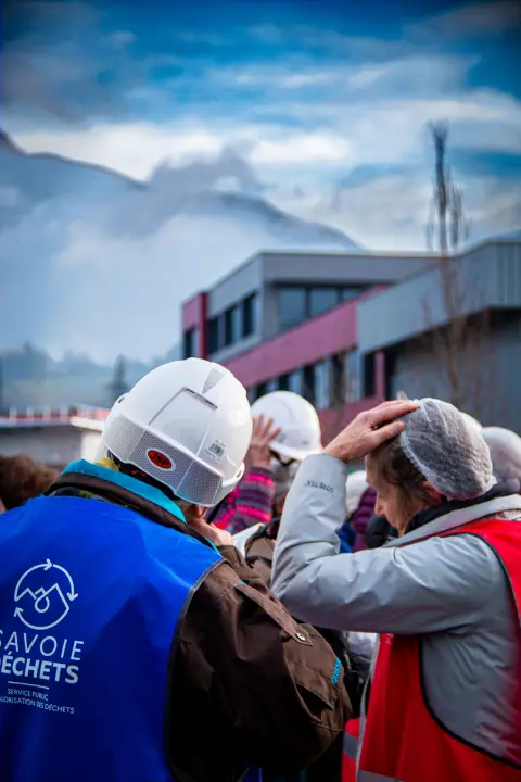 Visite guid&eacute;e du parcours p&eacute;dagogique ext&eacute;rieur, visiteurs de dos enlevant leurs charlottes avec en premier plan le gilet de s&eacute;curit&eacute; Savoie d&eacute;chets