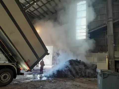 Camion deversant le compost apr&egrave;s maturation. Il fume puisqu'il est hygi&eacute;nis&eacute; par le biais d'un caisson d'hygi&eacute;nisation qui chauffe la mati&egrave;re &agrave; 65 degr&eacute;s pour acc&eacute;l&eacute;rer le processus de purification du compost.