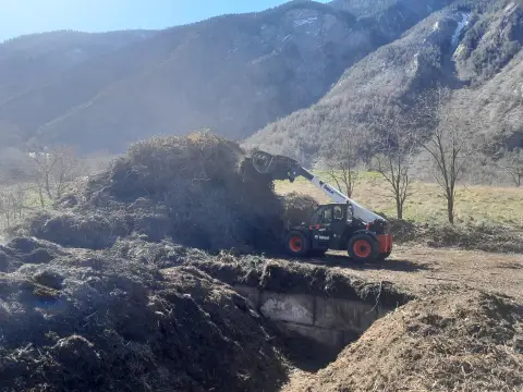 Plateforme de compostage de Maurienne &agrave; saint Julien Mont Denis, o&ugrave; l'on voit un tracteur soulevant un tas de compost pour le brasser : il composte les d&eacute;chets verts produits sur le territoire ainsi que les d&eacute;chets alimentaires collect&eacute;s par le SIRTOM.